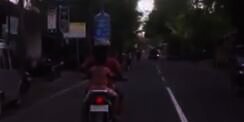 Ibu di Bali Naik Motor Bawa Galon Air Mineral di Kepala 