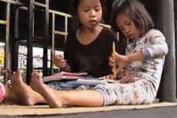 Foto Menyedihkan Gadis Kecil Kerjakan PR di Pinggir Jalan