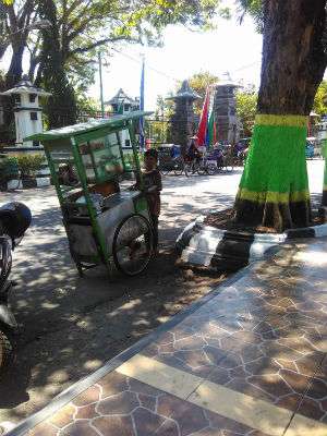 Bocah penjual bakso mendorong gerobaknya