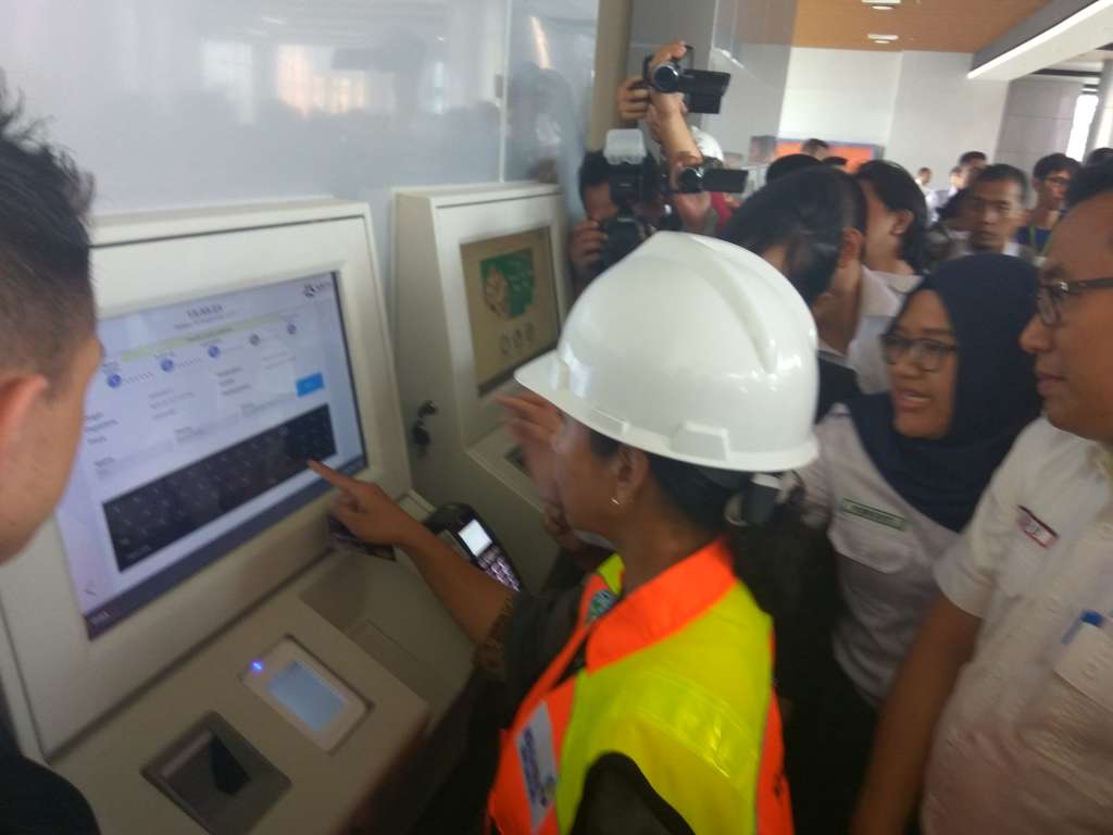 Rini membeli tiket kereta bandara.