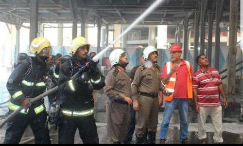 Para pekerja dan pemadam kebakaran membantu memedamkan api