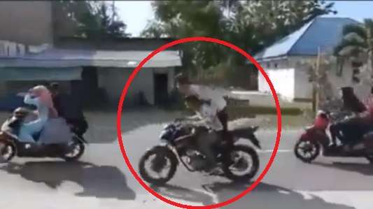 Dua remaja boncengan sepeda motor saat konvoi.