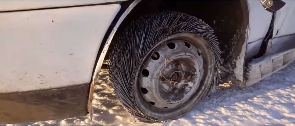 Seorang pria mengganti salah satu bannya dengan ban paku.