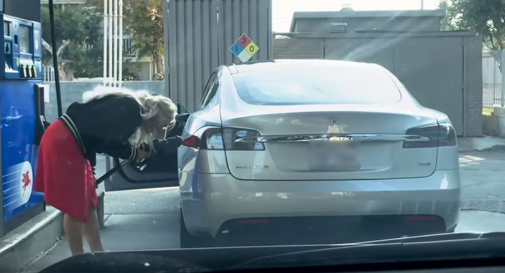Perempuan ini mengisi mobil listrik dengan gas.