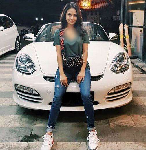 Dia bersandar di depan mobil Porsche.