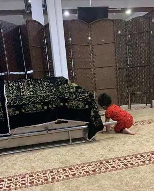 Afan bermain di sekitar keranda jenazah orang tuanya.