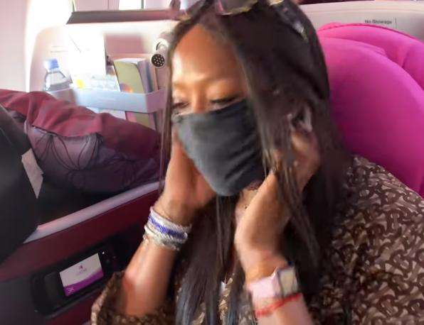 Naomi juga memakai masker di pesawat.