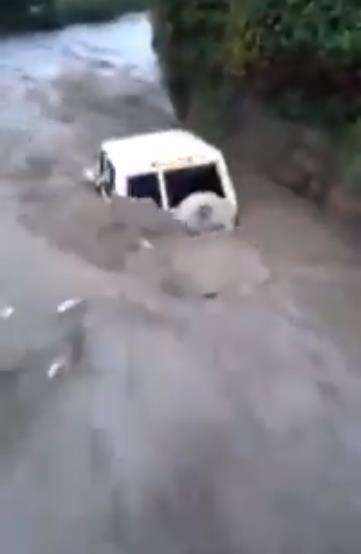 Jip berwarna putih nekad menyeberangi banjir berarus deras.