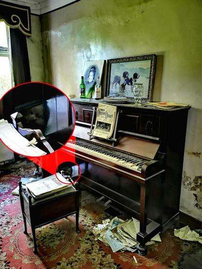 Tampak sosok wajah seram seperti boneka 'Chuky' di balik piano tua.
