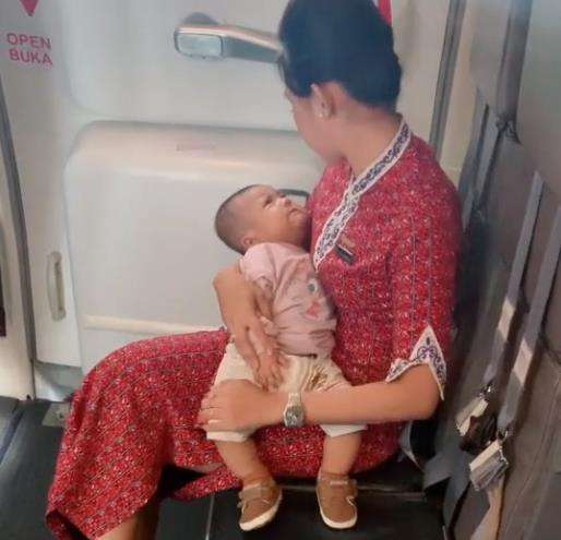 Pramugari gendong bayi selama bertugas.