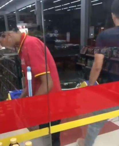 Tidak jauh dari wanita itu ada karyawan minimarket sedang menyapu.