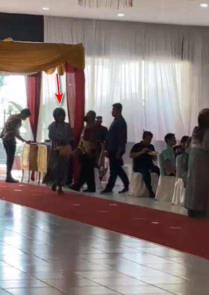 Tampak seorang ibu berjalan menuju pelaminan.