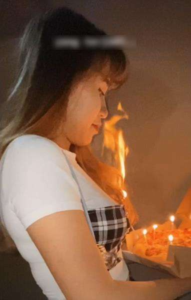 Rambutnya disambar api dari lilin di atas pizza.