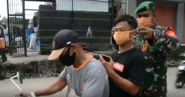 Anggota TNI memakaikan masker kepada pelanggar protokol kesehatan Covid-19.