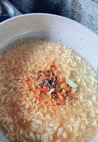Memasukkan bumbu yang disertakan di dalam bungkus mie instan.