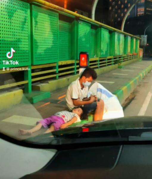 Dua bocah pemulung ketiduran di atas trotoar.