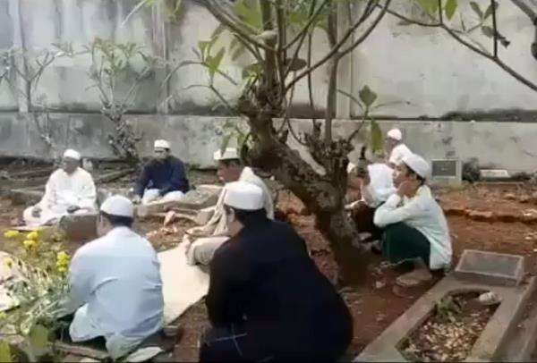 Warga tampak berziarah di sebuah kuburan.
