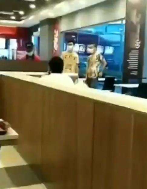 Seorang pria berkaos putih duduk membelakangi kamera.