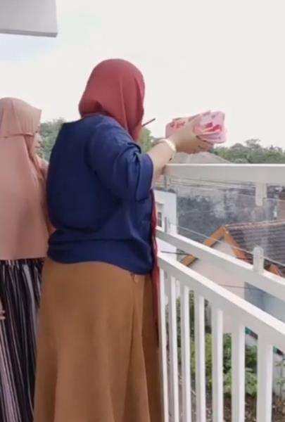 Ibu-ibu bagi-bagi uang dari atas loteng.