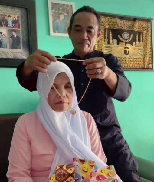 Adegan romantis suami pasangkan kalung emas untuk istri.