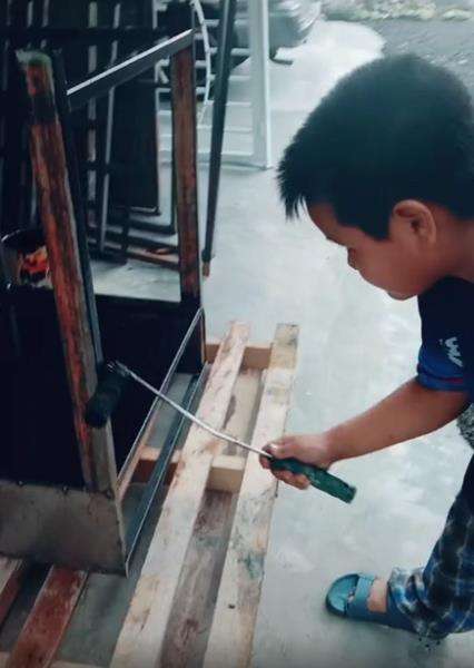 Dia bekerja mengecat meja di bengkel.