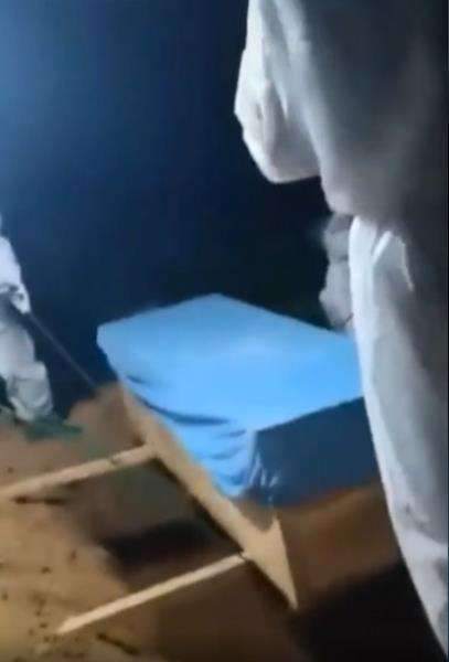Nakes siap menurunkan peti jenazah pasien Covid.
