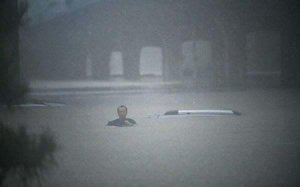 Seorang pria berusaha menyelamatkan diri dari banjir.