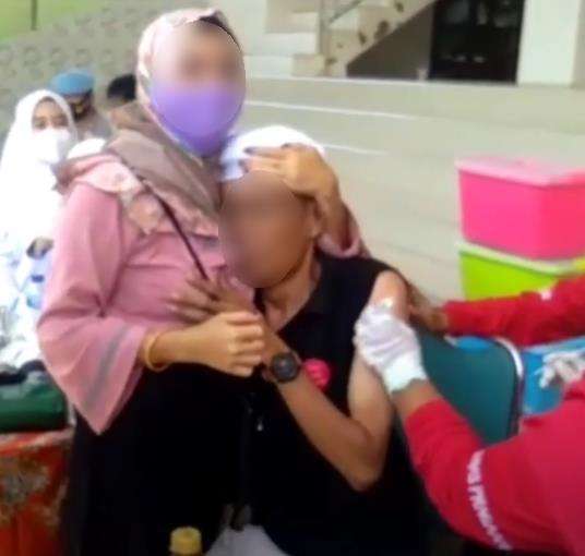 Suntik vaksin sambil peluk wanita.