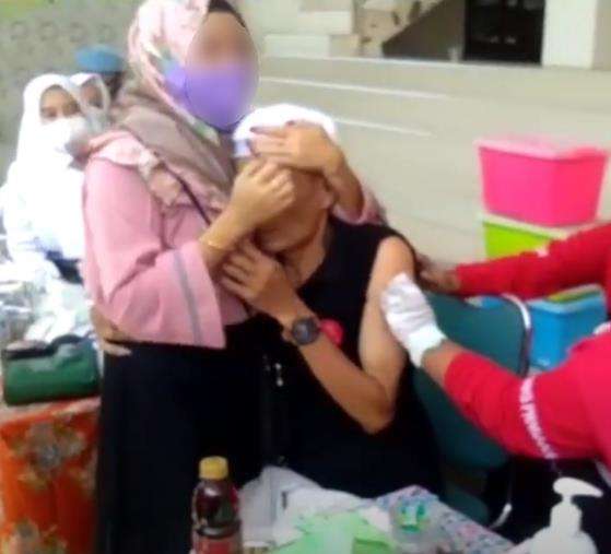 Suntik vaksin sambil peluk wanita.