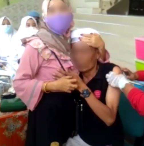 Suntik vaksin sambil peluk wanita.
