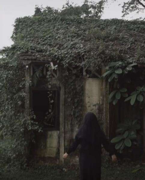 Gadis bergaun dan berkerudung hitam dekat rumah reyot pinggir hutan.