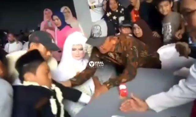 Pengantin pria pingsan di pangkuan pengantin wanita.