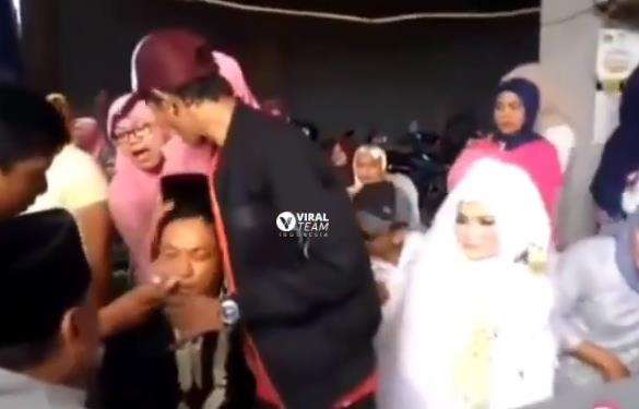 Pengantin pria pingsan di pangkuan pengantin wanita.