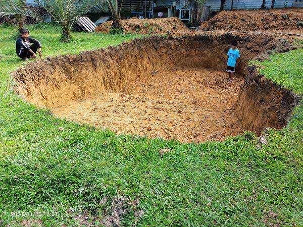 Seorang bapak bikin kolam renang sendiri dibantu anak-anaknya.