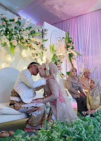 Momen pengantin pria hendak cium bibir istri di atas pelaminan.