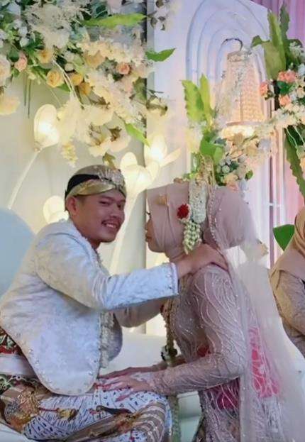 Momen pengantin pria hendak cium bibir istri di atas pelaminan.