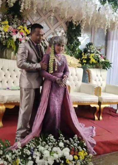 Sambil gendong anak istri tua dampingi suami duduk bersama istri muda di pelaminan.