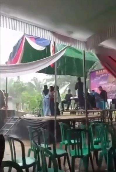 Lagi dangdutan di atas panggung saat hujan deras, disambar petir.