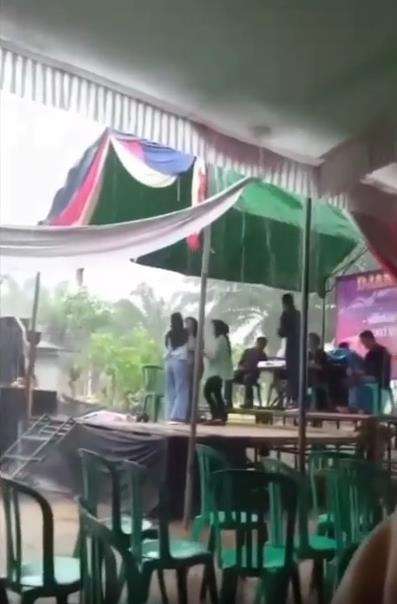 Lagi dangdutan di atas panggung saat hujan deras, disambar petir.