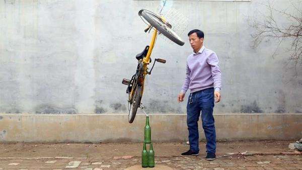 Yekun atraksi sepeda berdiri di atas botol.