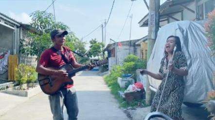 Emak-emak duet dengan pengamen.
