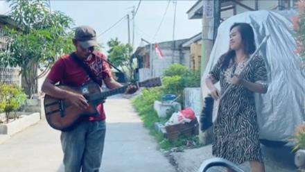Emak-emak duet dengan pengamen.