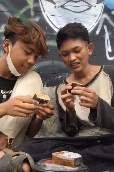 Dua pemuda makan dari tempat sampah.