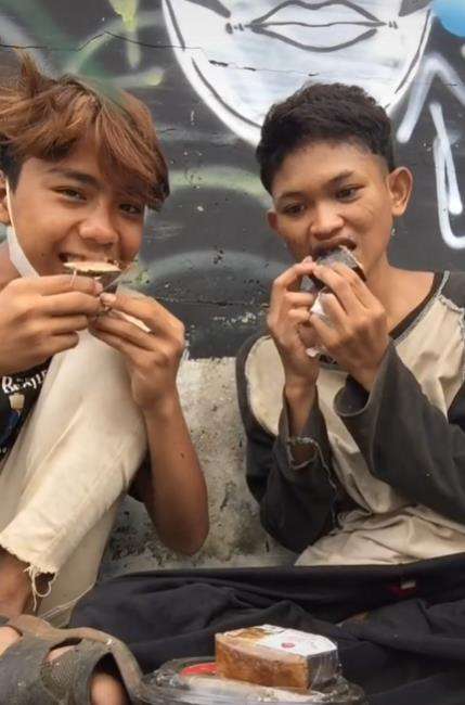 Dua pemuda makan dari tempat sampah.