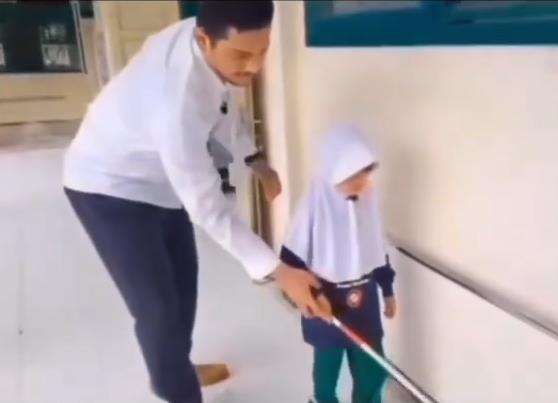 Guru mengajar murid penyandang tunanetra mengenal lingkungan.