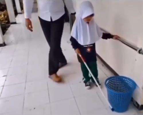Guru mengajar murid penyandang tunanetra mengenal lingkungan.