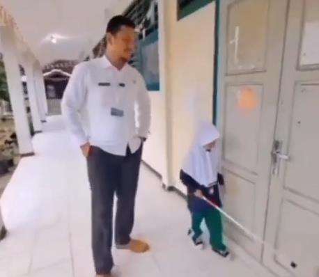 Guru mengajar murid penyandang tunanetra mengenal lingkungan.