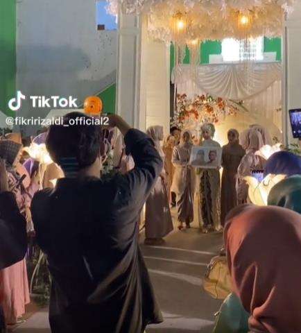 Pengantin wanita bawa foto orangtua di hari pernikahannya.
