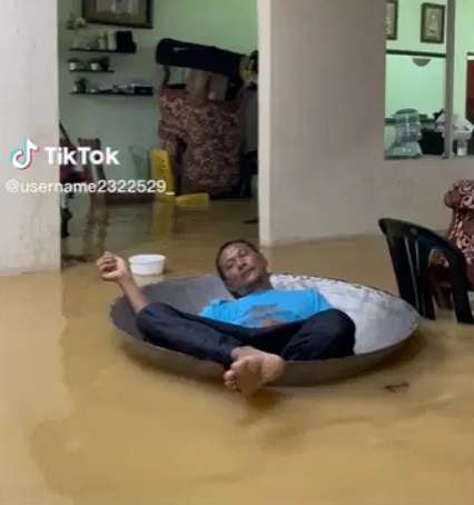 Pria Ini Santai Rebahan di Kuali Besar Meski Rumah Terendam Banjir