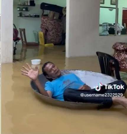 Pria Ini Santai Rebahan di Kuali Besar Meski Rumah Terendam Banjir